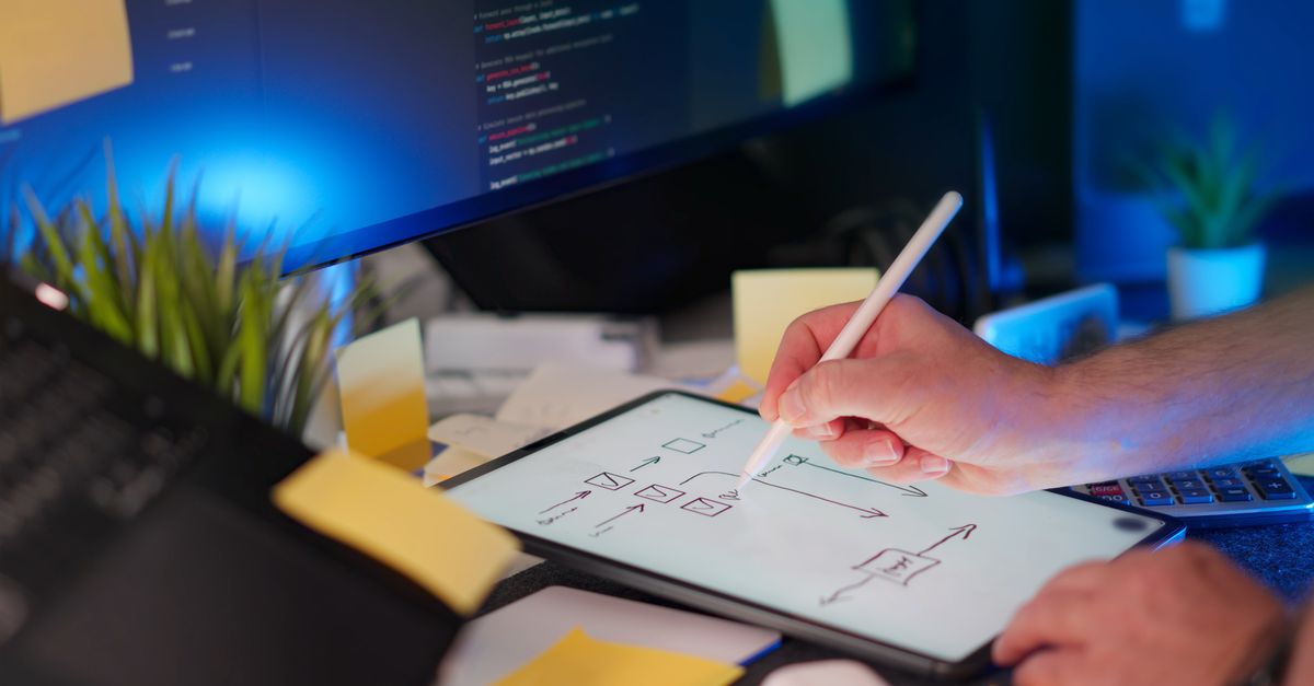 Un espace de travail dynamique comprenant des croquis numériques sur une tablette et du code sur un écran, présentant un environnement à la pointe de la technologie.